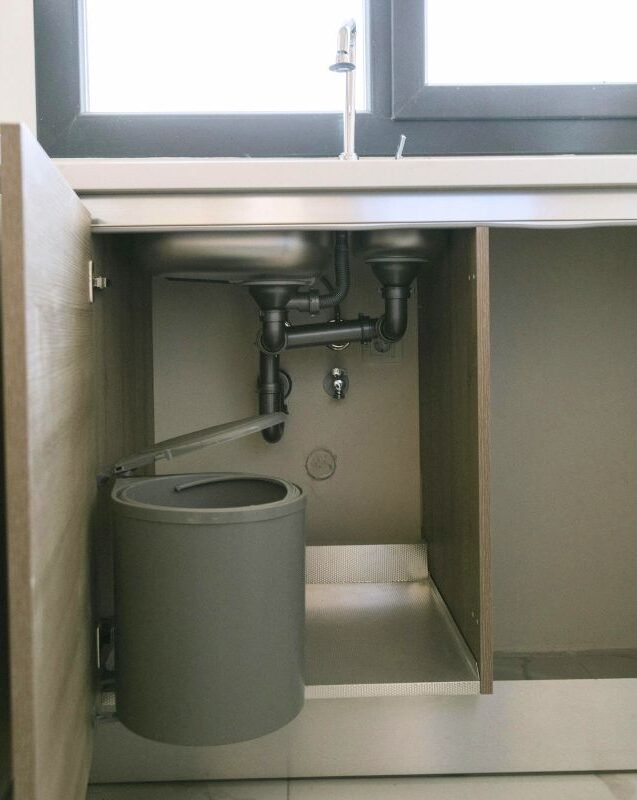 Interior del mueble bajo el fregadero sin organizar